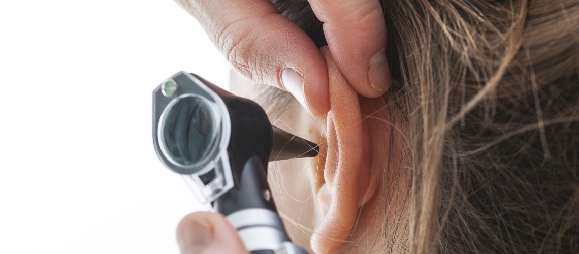 Closeup of examining ear with an otoscope